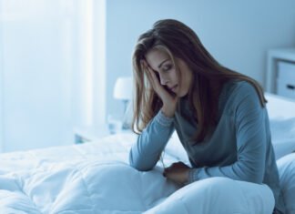 Depressed woman awake in the night, she is touching her forehead and suffering from insomnia